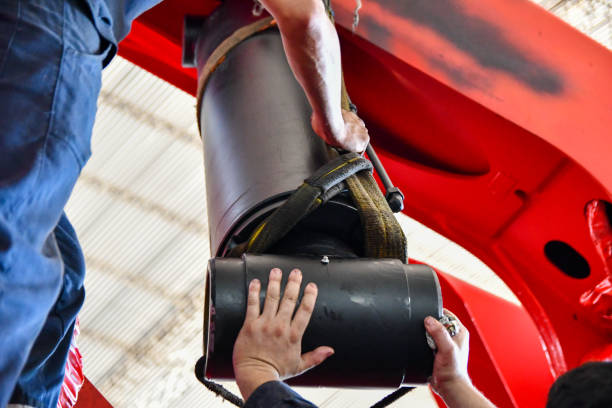 Latin men working as a team and using their hands to assemble a crane hydraulic cylinder