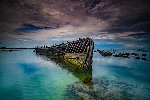 Old wooden shipwreck half sumerged in water