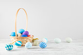 Easter Eggs in a Basket on White Wooden Background