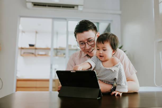 learning time of baby girl watching cartoon on his father's tablet. - father digital tablet asian ethnicity daughter imagens e fotografias de stock