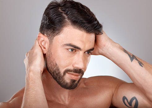 Face, beauty and a man with clean, glow and healthy skin on a grey studio background for skincare, dermatology and hygiene. Headshot of a male with a barber haircut and cosmetics for self care