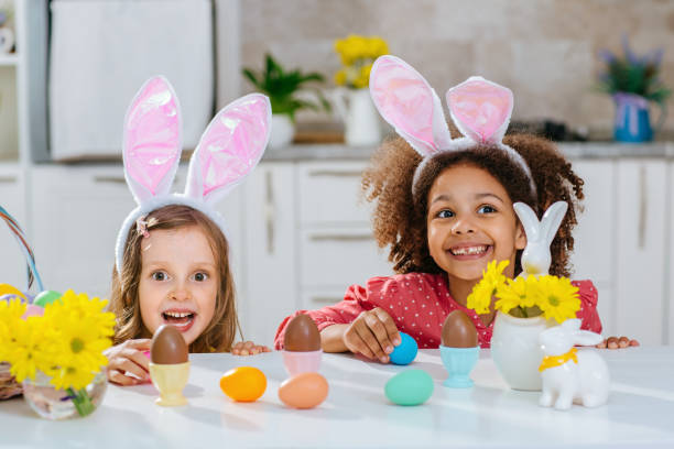 istock Two girls with Bunny ears on her heads is happy find a chokolate eggs after Easter egg hunt. 1471918447