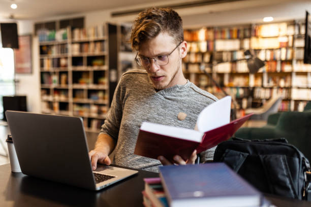 istock Young man with eyewear working on his laptop in a library studying 1471918818