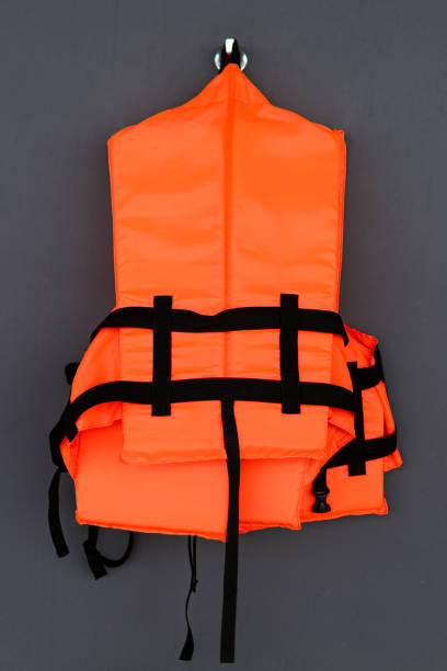 orangefarbene schwimmweste auf grauem hintergrund - life jacket isolated life belt nobody stock-fotos und bilder