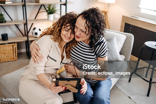 istock Mother and daughter look at framed pictures together 1471918978