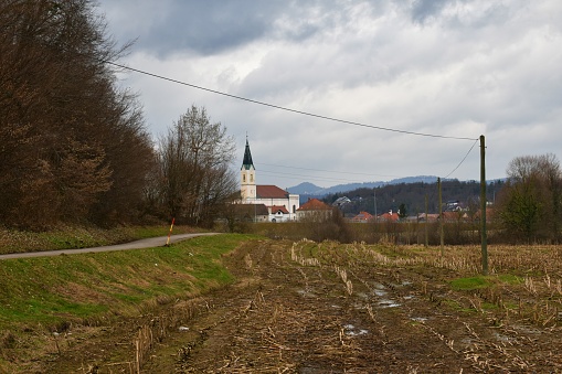 Church in the town of Vrhnika in Notranjska Slovenia with a field and a road leading towards the town