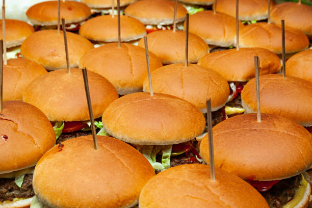 lots of hamburgers with cutlets, cheese and vegetables and wooden sticks tucked in them. - food elegance cutlet restaurant imagens e fotografias de stock