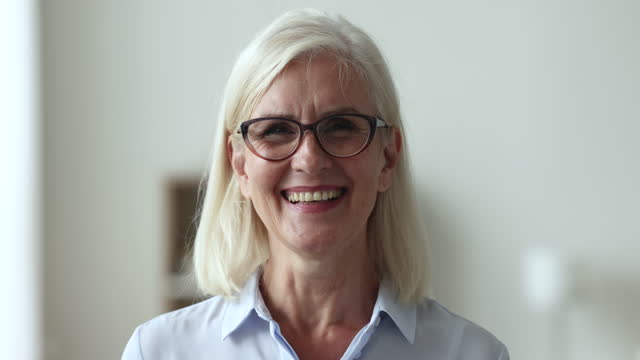 Happy mature businesswoman in glasses pose smile staring at camera