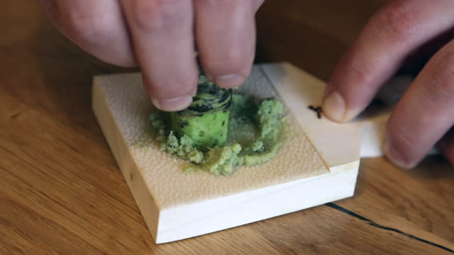 Japanese sushi chef preparing grated wasabi from fresh green rhizome