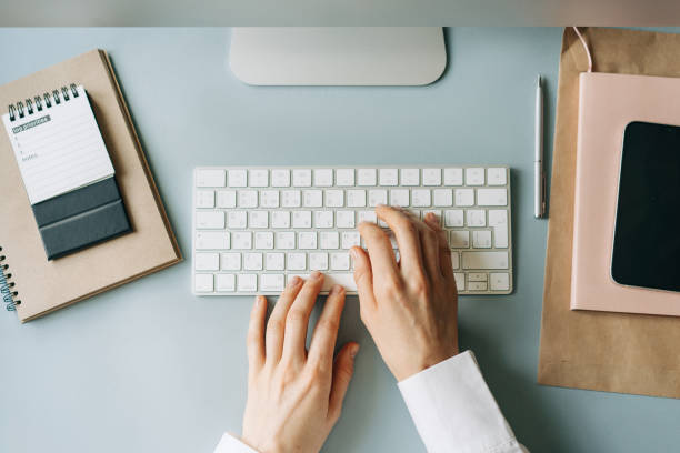 istock Elegant female hands typing on a computer keyboard, top view of a modern workplace. 1471924343