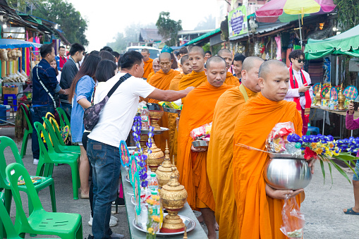 Luang Prabang, Laos - August 21 2016: Laotian people making offerings to Buddhist monks during traditional morning alms giving ceremony