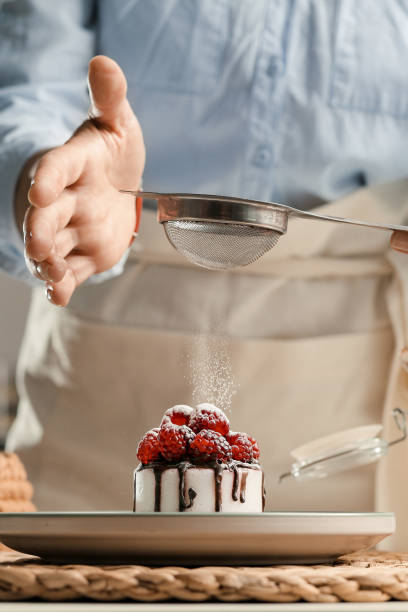istock Housewife prepares a cupcake, sprinkles with sugar. 1471925880