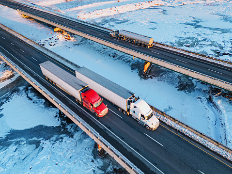Aerial view of semi trucks crossing a frozen tidal river.