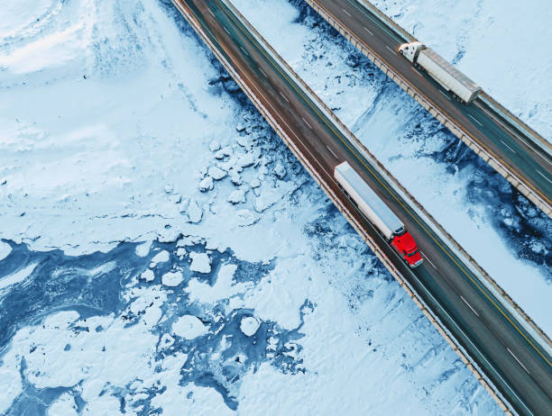 Aerial view of semi trucks crossing a frozen tidal river.