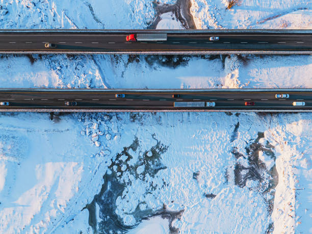 Aerial view of semi trucks crossing a frozen tidal river.