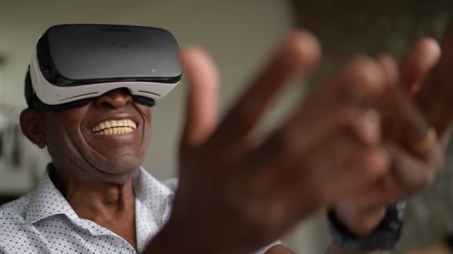 Senior man using virtual reality glasses at home