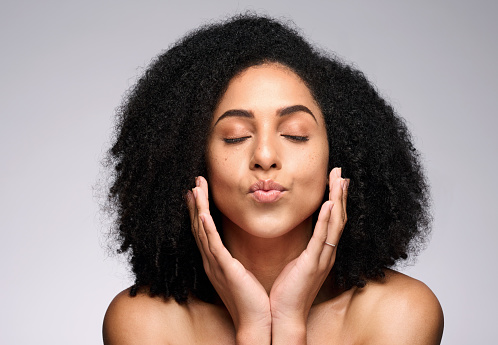 Face kiss, skincare beauty and black woman with eyes closed in studio isolated on a gray background. Natural cosmetics, makeup and young female model pouting lips satisfied with spa facial treatment.