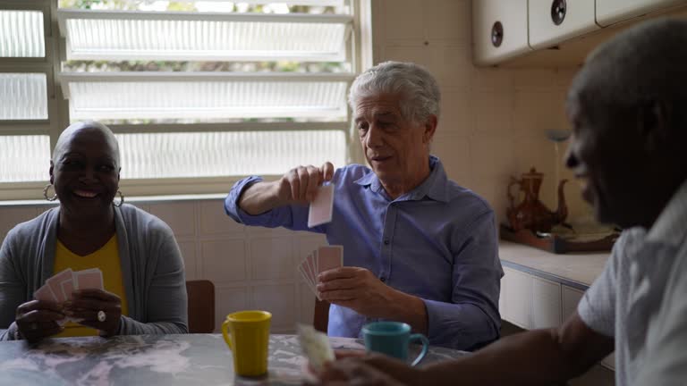 Senior friends playing cards at home