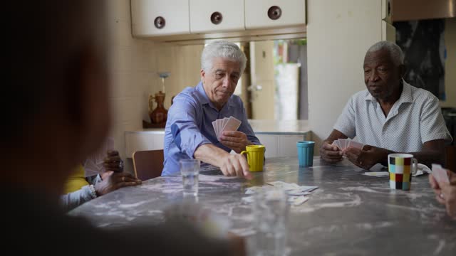 Senior friends playing cards at home