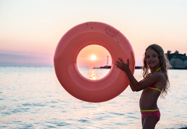Portrait cute small girl holding inflatable ring with sun in center