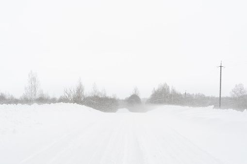 Big snowstorm on the rural road. Winter scene with extreme weather. Nature background