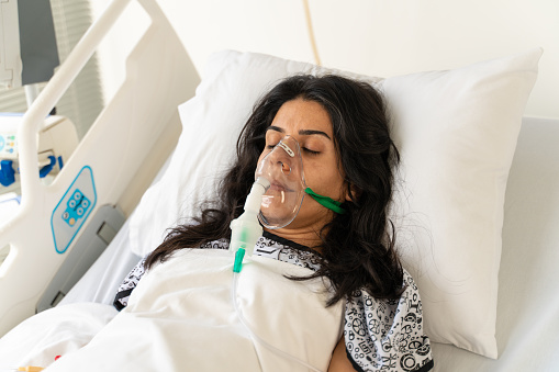 Woman with Ventilator mask on Hospital bed
