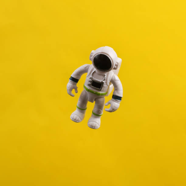 istock Toy astronaut model flying in antigravity on a yellow background 1471940574