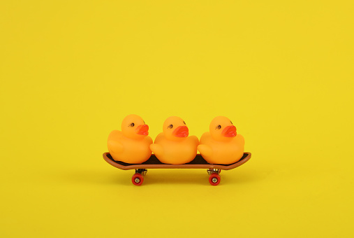 Rubber ducks ride on skateboard, pink background