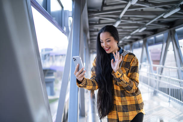 istock Smiling young multiracial  woman, having a video call on the phone, while walking under a pedestrian bridge 1471942345