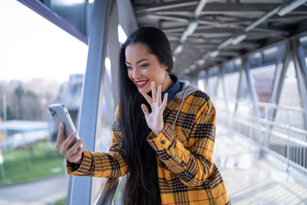 istock Smiling young multiracial  woman, having a video call on the phone, while walking under a pedestrian bridge 1471942347