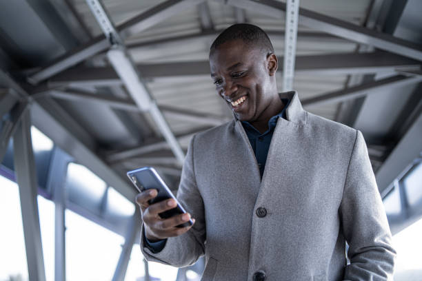 istock Smiling african-american man, messaging and surfing the net on his mobile, while standing under a pedestrian bridge 1471942351