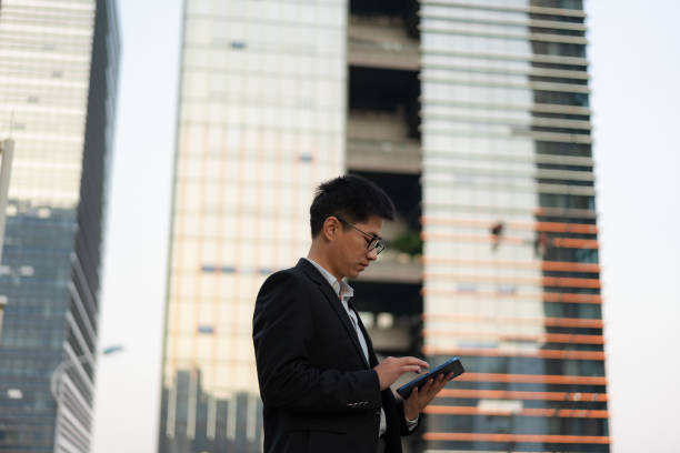 istock Chinese male office worker using tablet outdoors 1471943365