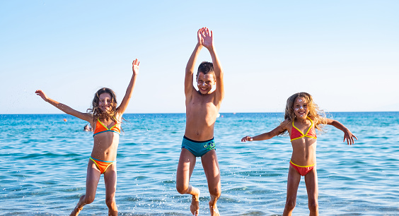 Children on the beach are posing and having fun, they jumped.