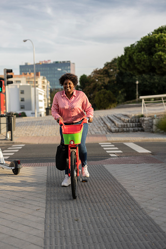 curvy young woman in modern city electric e-bike clean sustainable urban transport, happy african american backpacker traveling.