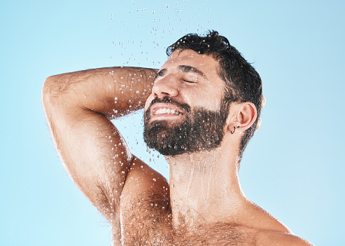 Shampoo, shower and cleaning with a model man washing his hair in studio on a blue background for natural care. Keratin, treatment and water with a male wet in the bathroom while grooming alone