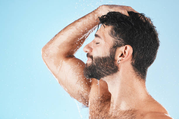 istock Head, hair and hygiene with a model man using shampoo for cleaning in studio on a blue background. Water, wet and wellness with a handsome male washing for haircare, hydration or keratin treatment 1471946419