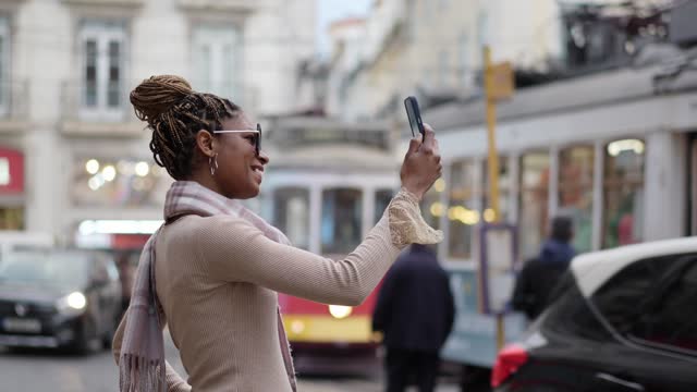 Woman taking photo with cell phone outdoors in Lisbon