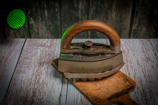 Old metal iron on old wooden blue table with chopping board