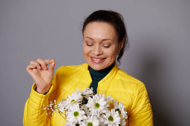 istock Middle-aged multi-ethnic woman smiles and plucks petals from chamomile. Fortune telling on a chamomile. 1471950573