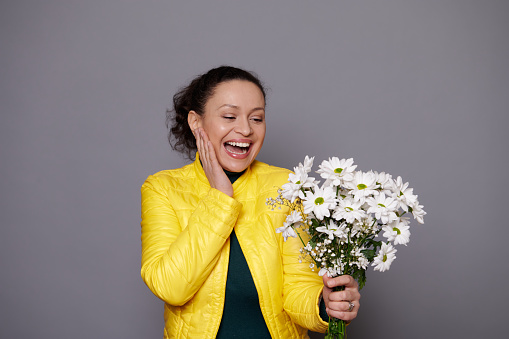 Amazed attractive middle-aged pretty woman, expressing happiness, feeling touched getting a cute flower bouquet for birthday, Women's, Mother's Day, festive event. Isolated portrait on gray background