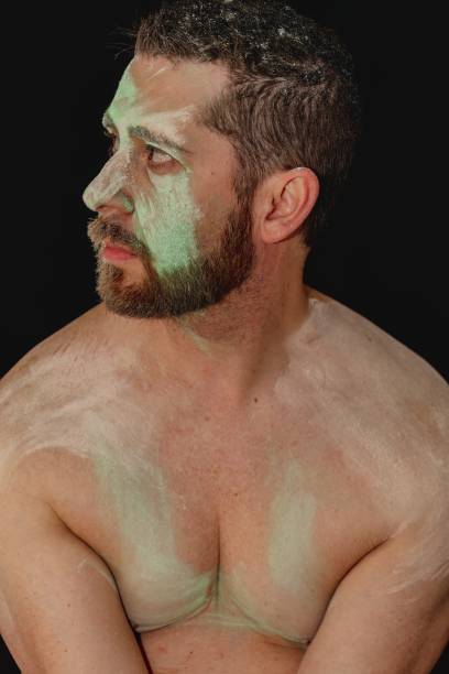 portrait of shirtless man with green body paint across face with beard portrait of shirtless man with green body paint across face with beard nudie suit stock pictures, royalty-free photos & images