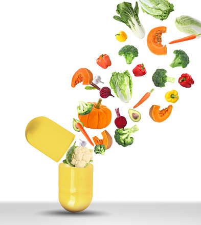 Dietary supplements. Capsule and different fresh vegetables flying on white background