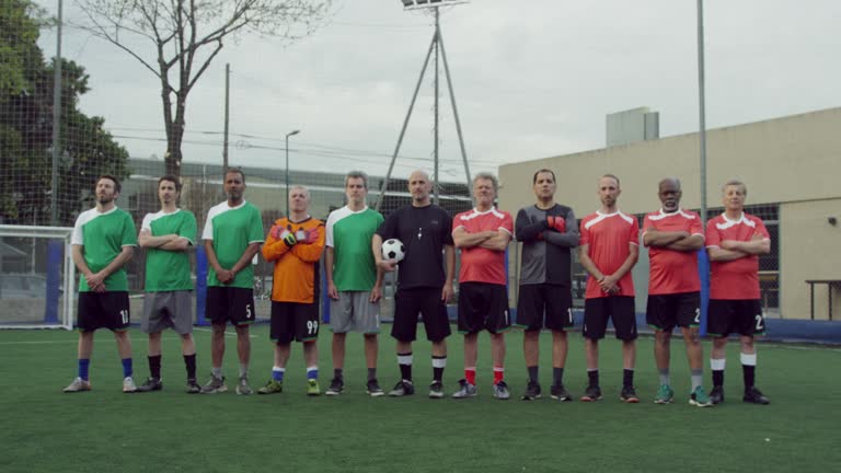 Two sport teams standing with referee before match at football field