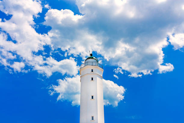 istock White lighthouse on a background of white clouds and blue sky. 1471955293