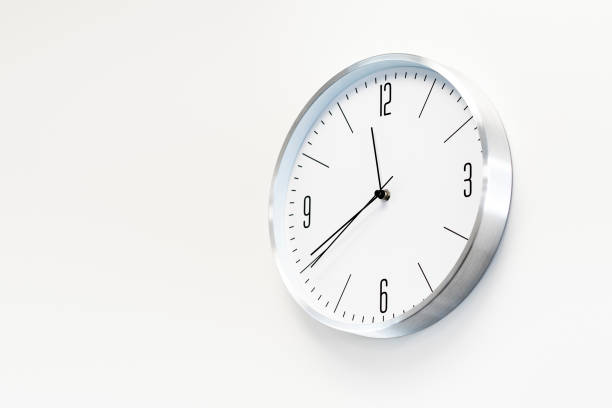 istock Stylish, round, white clock hangs on a white wall. Place for text, copy space. 1471956111