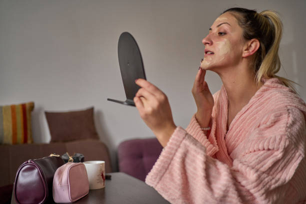 istock Young woman applying moisturizing cream on her face during morning routine 1471957193