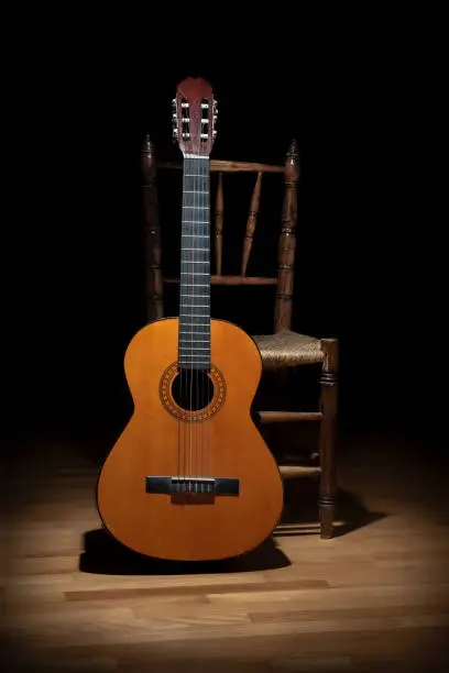 Classic guitar and an old chair on dark background in Seville, Spain. Typical spanish flamenco still life.