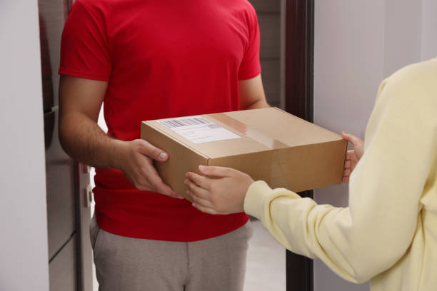 istock Woman receiving parcel from courier at home, closeup 1471960035
