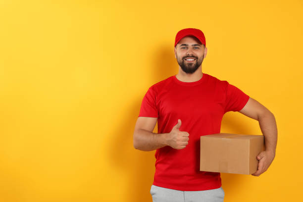 istock Courier holding cardboard box on yellow background, space for text 1471960665