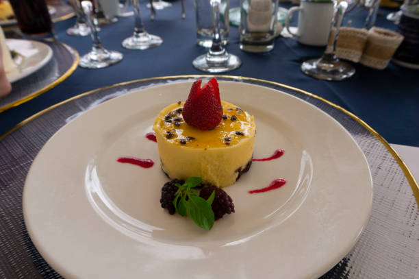 istock Passion fruit mousse garnished with strawberries and blackberries on a large white plate on a table with a blue tablecloth and crystal glasses 1471960699